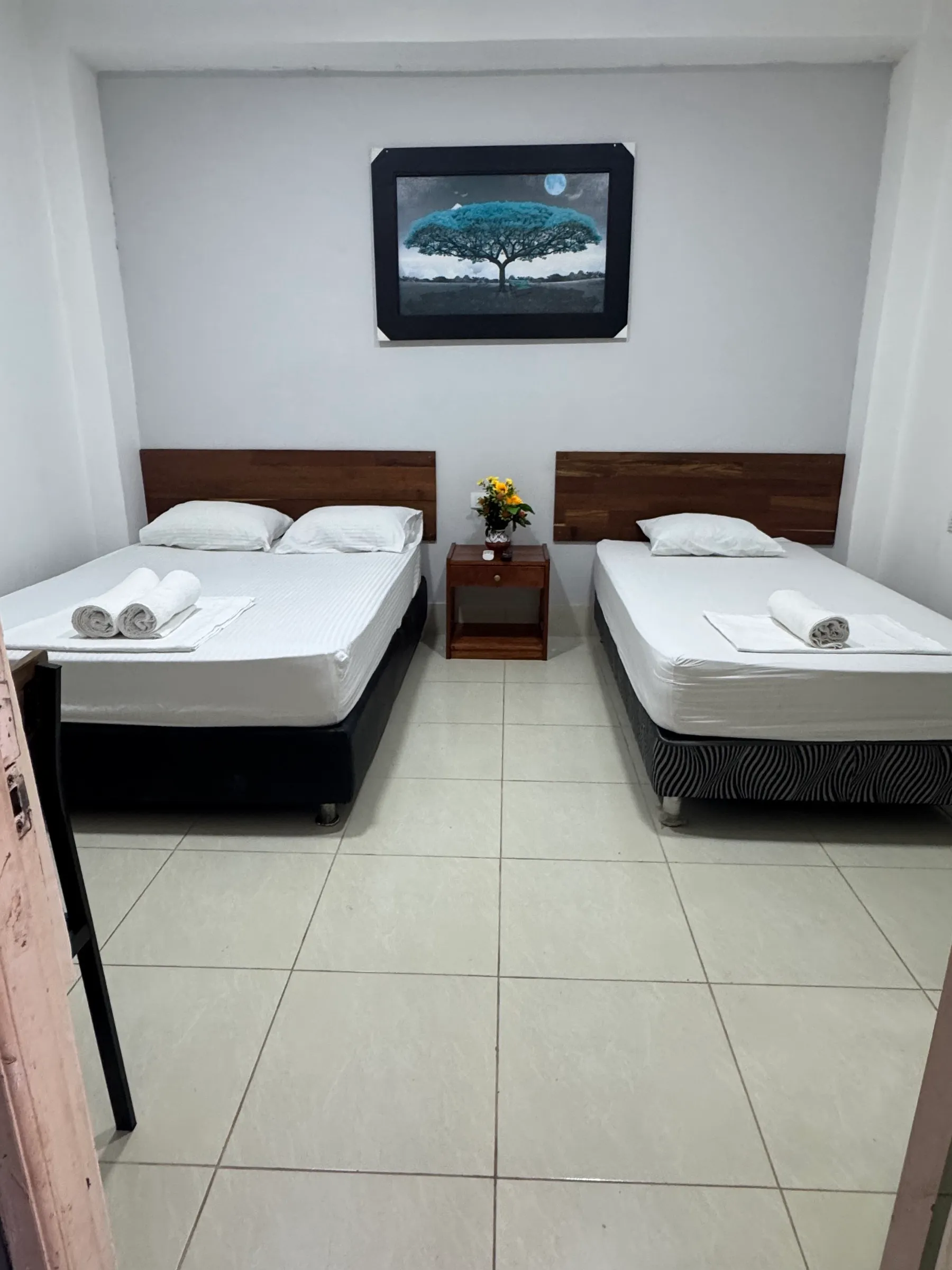 Habitación Doble con una cama de dos plazas, otra de plaza y media y cuadro sobre la pared