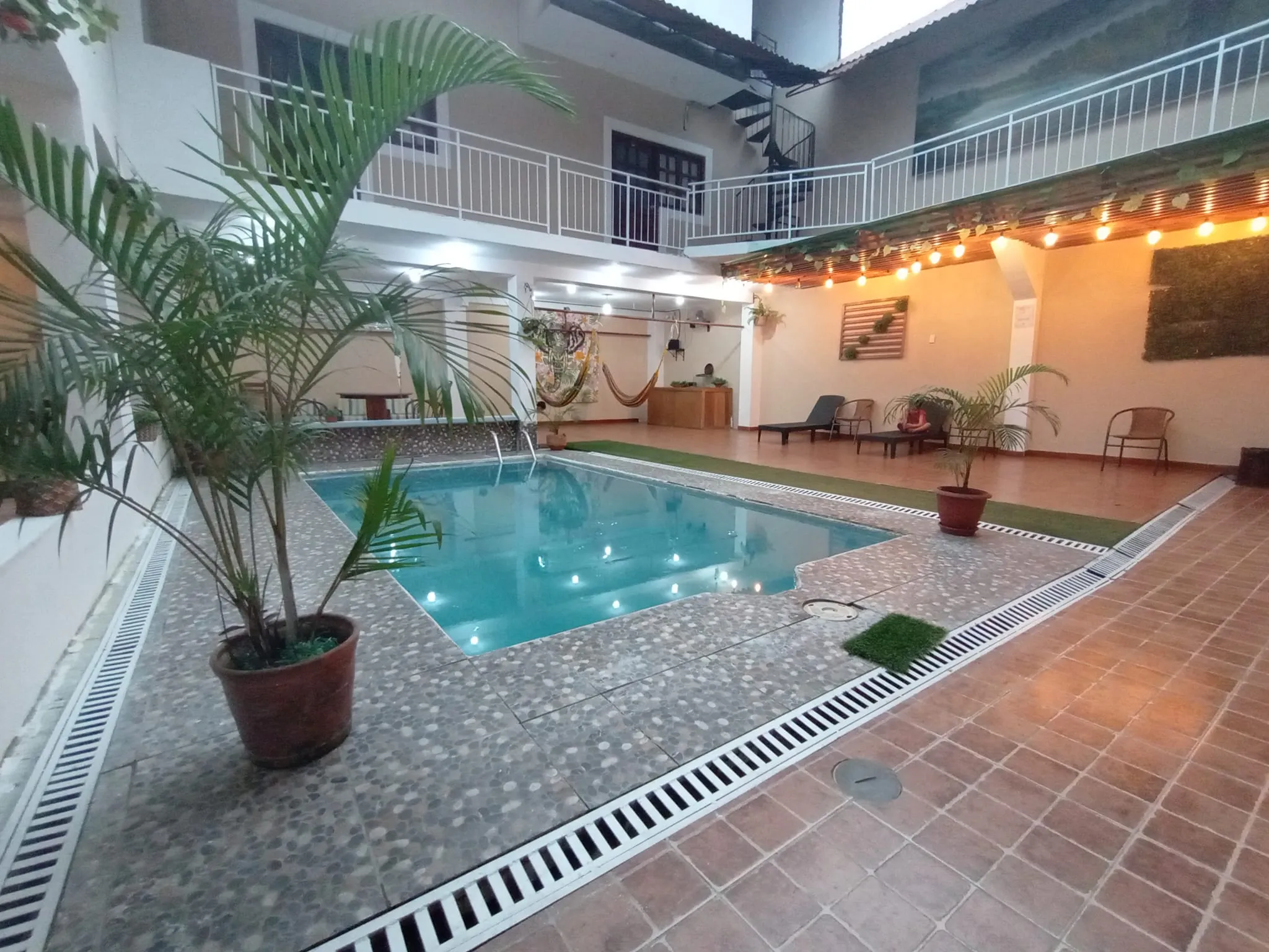 Patio interior de Iguana Haus con piscina, plantas y hamacas