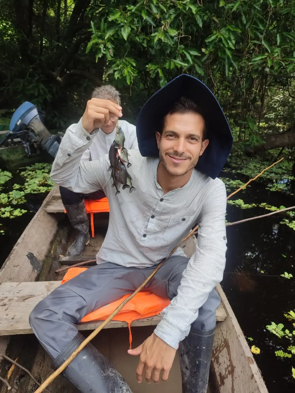 Visitante mostrando las pirañas que acaba de pescar desde la canoa